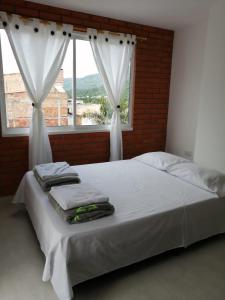 a bed with towels on it in front of a window at Hermoso apartamento familiar con parqueadero privado in San Gil
