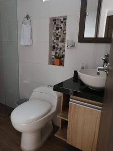 y baño con aseo blanco y lavamanos. en Hermoso apartamento familiar con parqueadero privado en San Gil
