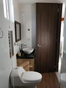 y baño con aseo blanco y lavamanos. en Hermoso apartamento familiar con parqueadero privado, en San Gil