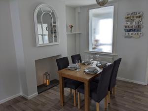 a dining room with a wooden table and black chairs at Ladybird Cottage in Weymouth