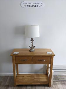 einem Holztisch mit einer Lampe darüber in der Unterkunft Ladybird Cottage in Weymouth