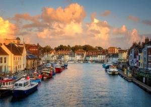 eine Gruppe von Booten, die in einem Fluss mit Gebäuden angedockt sind in der Unterkunft Ladybird Cottage in Weymouth