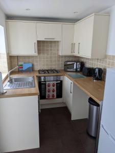 eine Küche mit weißen Schränken und einer Spüle in der Unterkunft Ladybird Cottage in Weymouth