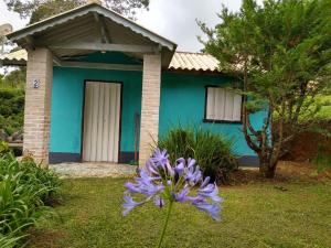 una casa azul con una flor delante en Sítio Monte Moriá Pousada en Santo Antônio do Pinhal