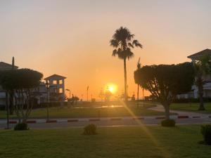 una puesta de sol en un parque con una palmera en Chez Dany à Residence Beralmar en Asilah