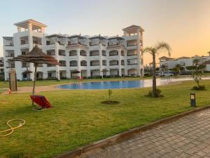 a large building with a pool in front of it at Chez Dany à Residence Beralmar in Asilah