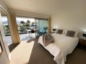 a bedroom with a bed and a balcony with a view at Picton Waterfront Apartments in Picton