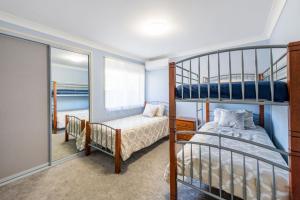 a bedroom with two bunk beds and a mirror at Rainforest Retreat in Iluka