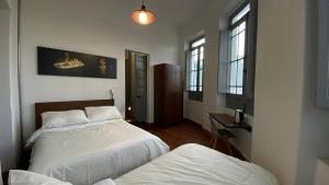 a bedroom with two beds and two windows at REPUBLICANA CASA HOSTAL - HABITACIÓN 3 EL DORADO in Bogotá