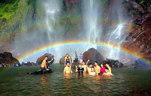 a group of people in the water with a rainbow in the background at RIVERSIDE PALM INN SG LEMBING in Sungai Lembing
