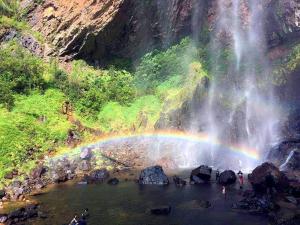 a rainbow over a pool of water with a waterfall at RIVERSIDE PALM INN SG LEMBING in Sungai Lembing