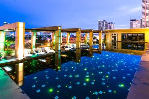 a hotel rooftop with a pool at night at Bella B All Suite Bangkok in Bangkok