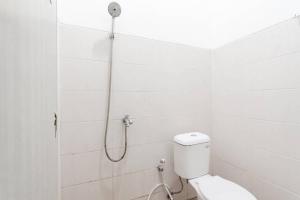 a white bathroom with a shower with a toilet at RedDoorz Syariah near Karawang Central Plaza in Karawang