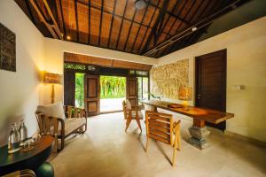 un salon avec une table et des chaises en bois dans l'établissement Uma Kalai, à Ubud