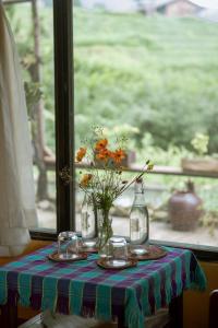 una mesa con un jarrón de flores y dos vasos en Desi house Ta Van Sapa, en Sa Pa