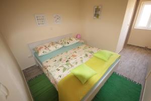 una piccola camera da letto con un letto con lenzuola verdi e gialle di Apartment Rustica with 2 bedrooms a Ljubač