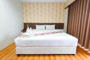 a bedroom with a large white bed and a window at Perfectroom Mansion in Hat Yai