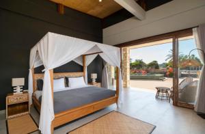 a bedroom with a canopy bed and a patio at Manduna Resort in Nembrala