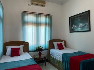 a hotel room with two beds and a window at RedDoorz Syariah @ Karang Pilang in Karangpilang