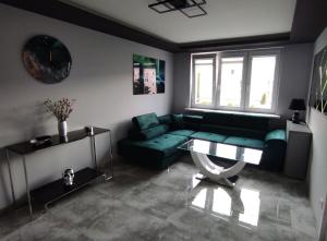a living room with a green couch and a table at Apartament Heaven in Ełk
