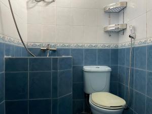 a blue tiled bathroom with a toilet and a shower at RedDoorz Syariah @ Karang Pilang in Karangpilang