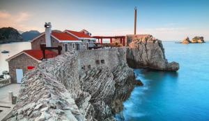 a building on a cliff next to the water at Vista Petrovac in Petrovac na Moru