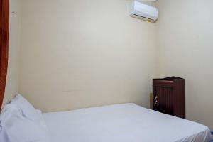 KejayanにあるKoolKost near Fakultas Teknik UGM Male Only - Minimum Stay 6 Nightsの白いベッドと木製キャビネット付きのベッドルーム1室が備わります。