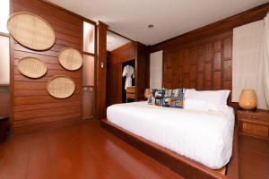 a bedroom with a white bed and wooden walls at ViengTara VangVieng Resort in Vang Vieng