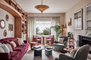 sala de estar con sofá rojo y sillas en Osborn House, en Bundanoon