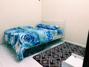 um quarto com uma cama com um cobertor azul e um tapete em QQ HOMESTAY BACHOK KANDIS em Bachok