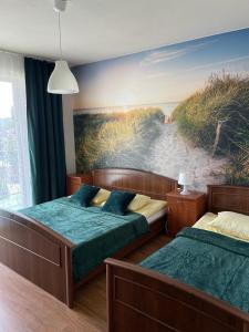 a bedroom with two beds and a painting of a beach at Emada- Pokoje Gościnne i Studia in Ostrowo