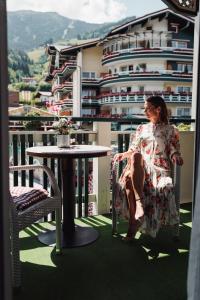 フューゲンにあるHotel Kohlerhofのバルコニーのテーブルに座る女性