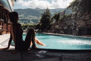 a woman sitting next to a swimming pool at Kohlerhof - 4 Star Wellness & Active Hotel in Fügen