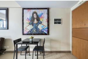 ein Esszimmer mit einem Tisch und einem Gemälde an der Wand in der Unterkunft Studio at Newport World Airport Area Prime Location in Manila