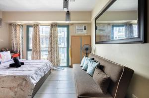 ein Schlafzimmer mit einem Bett, einem Sofa und einem Spiegel in der Unterkunft Studio at Newport World Airport Area Prime Location in Manila