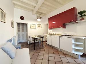 uma cozinha com armários vermelhos e uma mesa num quarto em Trastevere Rome’s Heart charming apartment 88 em Roma