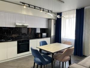 a kitchen with a table and blue chairs in a room at Новостройка с дизайнерским ремонтом in Petropavlovsk