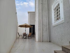 a table and chairs with an umbrella on a patio at دور فخم ومتكامل بالقرب من عسير مول in ‘Aryam
