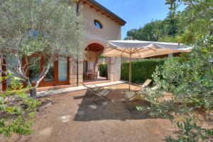 un patio con sombrilla y sillas frente a una casa en Villa Faccioli Magnolia And Oleandro With Shared Pool - Happy Rentals, en Colognola ai Colli