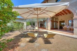 un grupo de sillas y una sombrilla frente a una casa en Villa Faccioli Magnolia And Oleandro With Shared Pool - Happy Rentals, en Colognola ai Colli