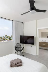 a bedroom with a bed and a tv and a chair at Stylish & Spacious 3 bedroom apartment by the Sea in Netanya