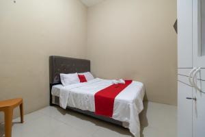 Schlafzimmer mit einem Bett mit einer roten und weißen Decke in der Unterkunft RedDoorz near Palembang Trade Center 4 in Sukarami
