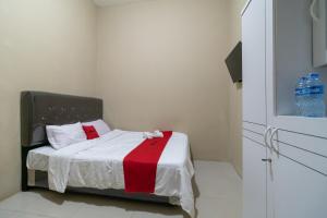 ein kleines Schlafzimmer mit einem Bett mit einer roten und weißen Decke in der Unterkunft RedDoorz near Palembang Trade Center 4 in Sukarami + 10 Fotos
