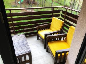 twee stoelen met gele kussens op een balkon bij s23 green in Zlatibor