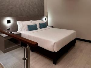 a bedroom with a large bed with blue pillows at The Litton Hotel by Carterson in Naga