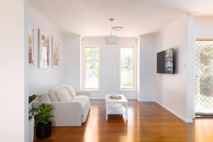 a white living room with a white couch and windows at Adorable 1-bedroom Kuzman Guesthouse in Mudgee
