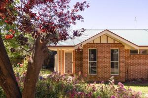 a brick house with flowers in front of it at Adorable 1-bedroom Kuzman Guesthouse in Mudgee