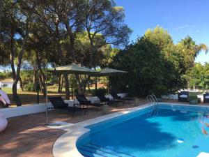 uma piscina com cadeiras e um guarda-sol em VILLA DE LA LUZ Luxury Guesthouse em El Portil
