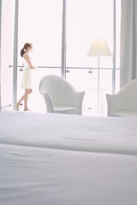 Una mujer con un vestido blanco caminando en un dormitorio en Estalagem Da Ponta Do Sol en Ponta do Sol