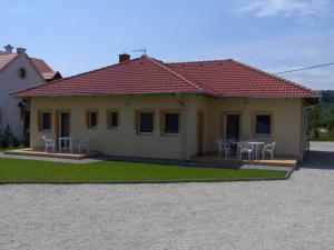 a house with a table and chairs in front of it at Petra Apartmanház in Kehidakustány